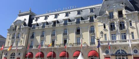 A large hotel with multiple balconies and red awnings.