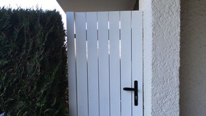 A white door with vertical slats and a black handle, set in a concrete step with a textured wall beside it. - Cabourg Mon Amour (Cabourg)