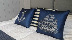 A bed with white bedding and two navy blue pillows with nautical designs. - Sunny Paradise-s?oneczny Raj (Sarbinowo)