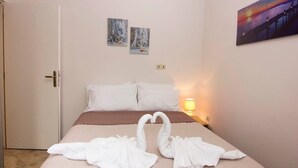 Een hotelkamer met een bed, twee wanddecoraties en een nachtkastje met een lamp.