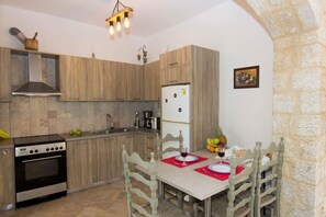 Una cocina con armarios de madera, una estufa y una mesa de comedor para dos, con individuales rojos.