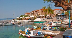 Un port de plaisance avec des bateaux amarrés, un bâtiment situé au bord de l’eau et un ciel dégagé.