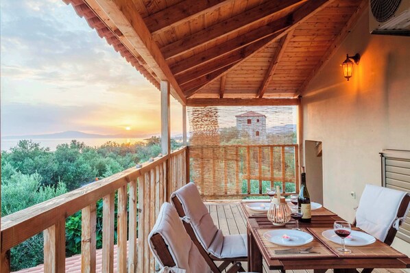 Una terraza de madera con una mesa lista para cenar, con vistas a un paisaje pintoresco con un atardecer.