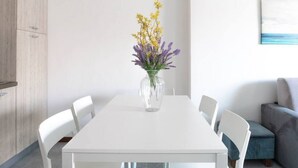 A modern dining area with a white table, clear glass vase with flowers, white chairs, and a grey sofa. - Apartment on the beach facing Lake Como. Air conditioning, wifi, internal parking and beach access are free!The house is located right in front of the lake, from where you can enjoy the beautiful view of the lake. Bellano center and Bellano Tartavalle Te (Bellano)