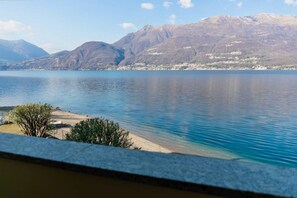 A lake with mountains in the background and a sandy beach area. - Apartment on the beach facing Lake Como. Air conditioning, wifi, internal parking and beach access are free!The house is located right in front of the lake, from where you can enjoy the beautiful view of the lake. Bellano center and Bellano Tartavalle Te (Bellano)
