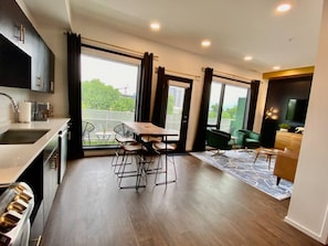 A modern kitchen with a dining area, large windows, and a view of greenery. - CHIC Modern Nashville Condo ★ POOL, PATIO, PARKING (Nashville)
