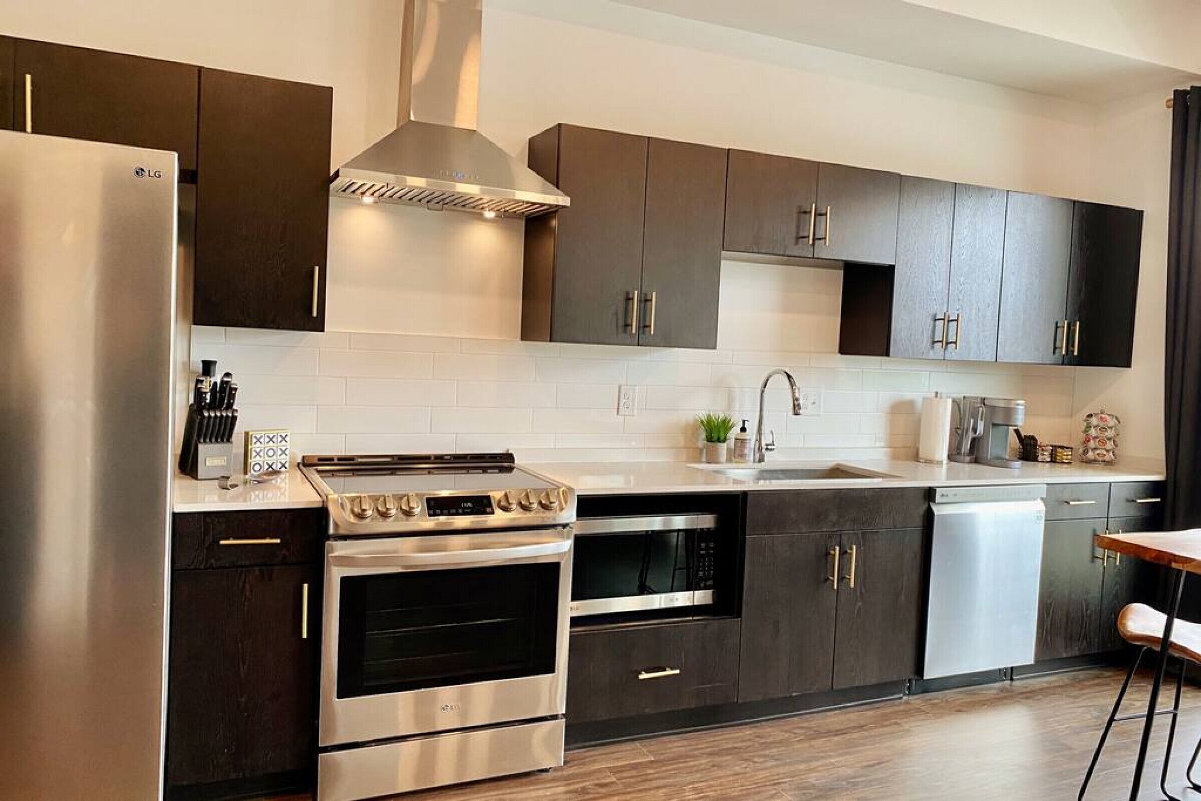 Une cuisine moderne avec des meubles de couleur sombre, des appareils électroménagers en acier inoxydable et un îlot central.