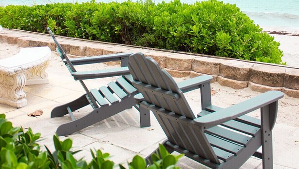 Deux fauteuils Adirondack sont placés face à une plage, offrant une vue sur l’océan.