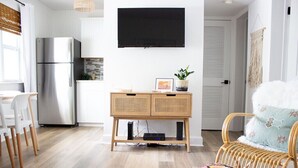 Un salon moderne avec une table basse en bois, un fauteuil en osier et un téléviseur fixé au mur.