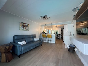 Uma sala de estar moderna com um sofá azul, cozinha e espaço para refeições.