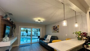 A modern kitchen with a central island, a dining area with yellow chairs, and a large sliding glass door leading to a backyard. - Perfect Fort Myers Getaway!  Close to beaches, downtown, nightlife.. (Fort Myers)