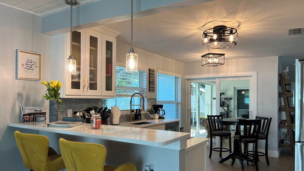A modern kitchen with a central island, bar stools, pendant lighting, and a view to the dining area. - Perfect Fort Myers Getaway!  Close to beaches, downtown, nightlife.. (Fort Myers)