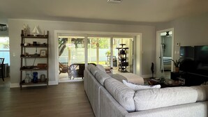 A living room with a sofa, a television, and a bookshelf. - Perfect Fort Myers Getaway!  Close to beaches, downtown, nightlife.. (Fort Myers)
