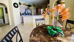 A dining area with a marble table, chairs, and a flower arrangement. - Southern Dunes Golf Views! 5 Bedroom Home by RedAwning (Haines City)