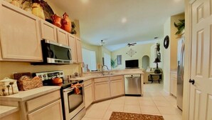A kitchen with a microwave, oven, and sink. There is a decorative rug on the floor. - Southern Dunes Golf Views! 5 Bedroom Home by RedAwning (Haines City)