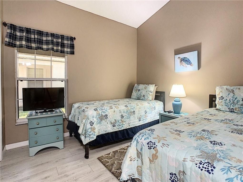 A bedroom with two beds, a television, a lamp, and a framed picture on the wall.