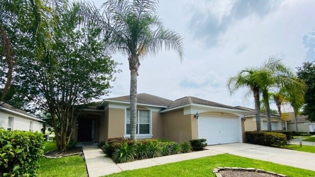 A residential house with a front yard, a driveway, and a garage. - Snow Birds Welcome- Southern Dunes Golf! 4 Bedroom Home by RedAwning (Haines City)