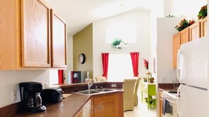 A compact kitchen with wooden cabinets, a built-in oven, and a refrigerator. - Snow Birds Welcome- Southern Dunes Golf! 4 Bedroom Home by RedAwning (Haines City)