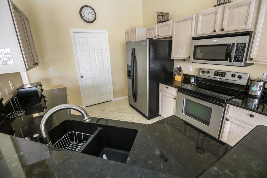 A kitchen with a refrigerator, microwave, oven, and sink.