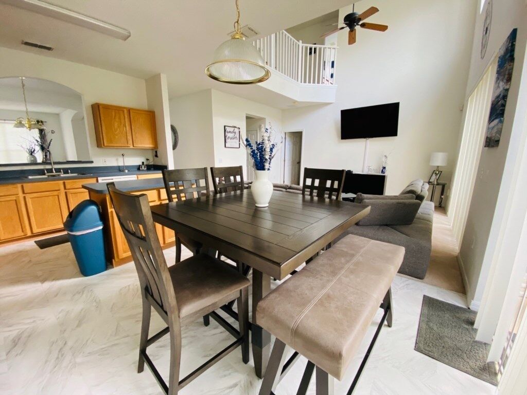 A modern kitchen with a dining table, chairs, and a ceiling fan.