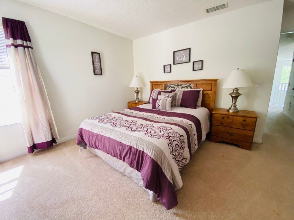 A bedroom with a bed, nightstands, a lamp, and a window with curtains.