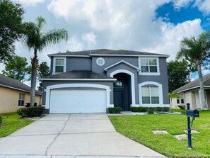 A two-story house with a front garage, a well-maintained lawn, and a mailbox.