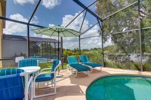 Un espace extérieur abrité comprenant une piscine, des chaises longues et un parasol.