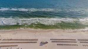 A beach with rows of sun loungers and umbrellas, a clear view of the ocean, and a sandy shore.