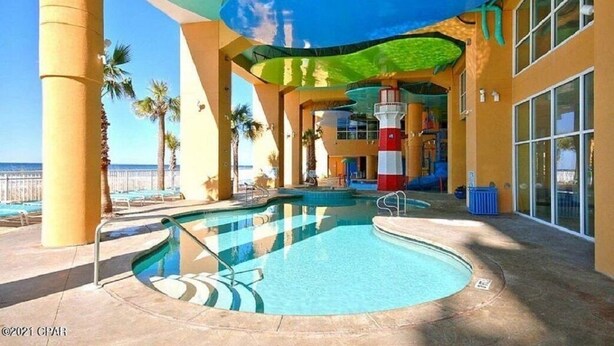 A pool area with a circular hot tub, lounge chairs, and a lifeguard tower.