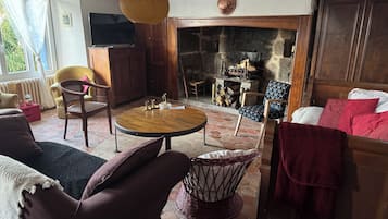 Een gezellige woonkamer met een open haard, comfortabele zitplaatsen en een televisie.