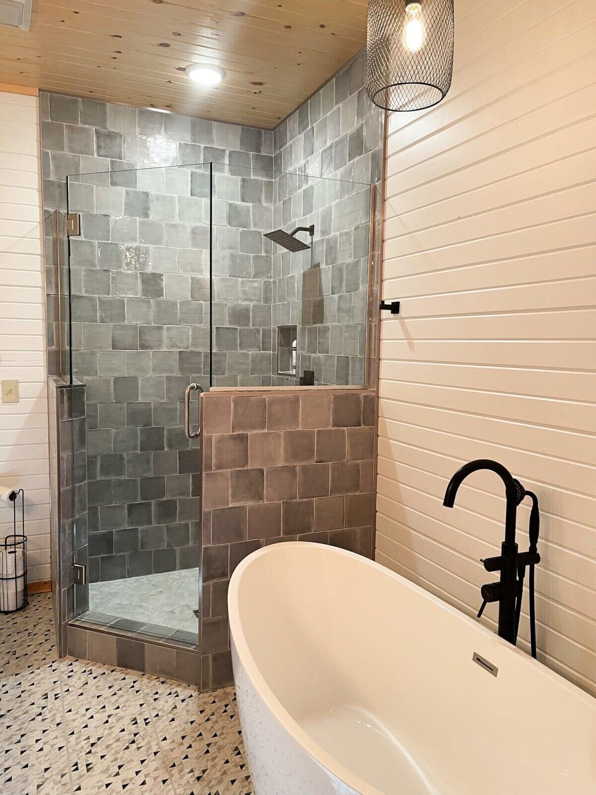 Een moderne badkamer met een douchecabine van glas, een vrijstaand bad en een houten plafond.