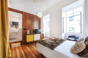 Un dormitorio moderno con piso de madera, una cama con manta suave, un televisor y un armario de madera.