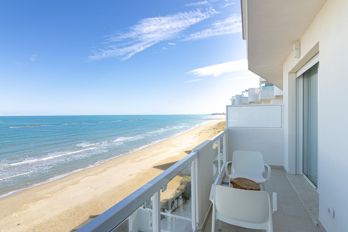 A balcony with a view of the beach and ocean.
