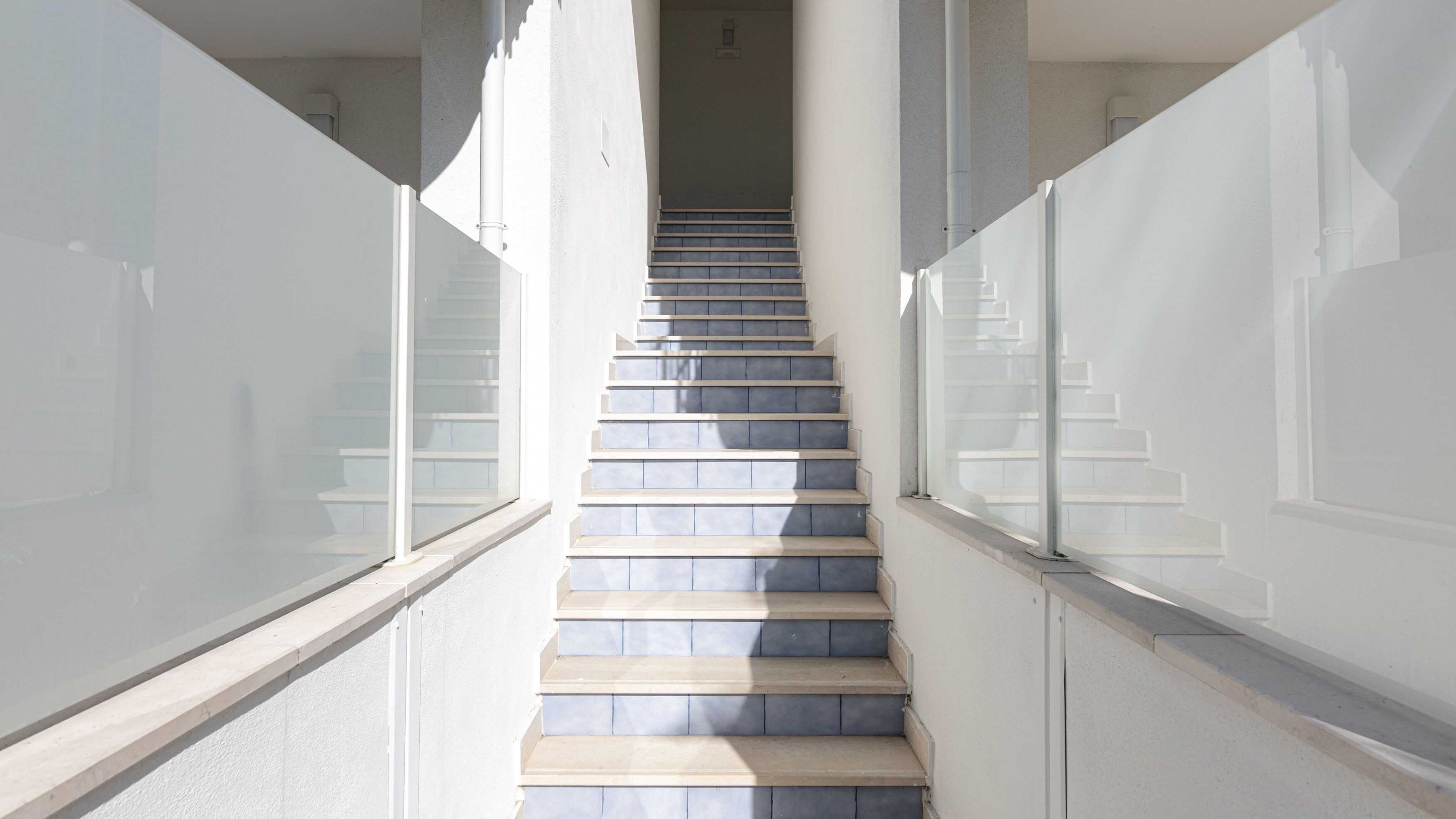 Una escalera con barandillas de vidrio que sube a un piso superior.