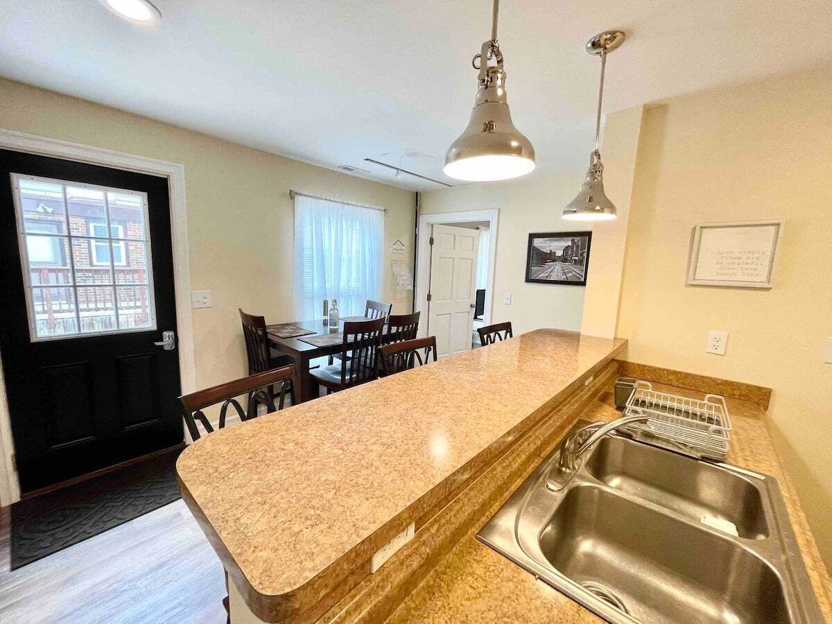 A kitchen with a granite countertop, stainless steel sink, and pendant lighting.