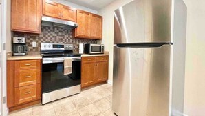 Eine Küche mit Holzschränken, einem Edelstahlkühlschrank, einer Mikrowelle und einem Backofen.