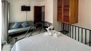 A hotel room with a bed, a sofa, a TV, and a wooden wardrobe.