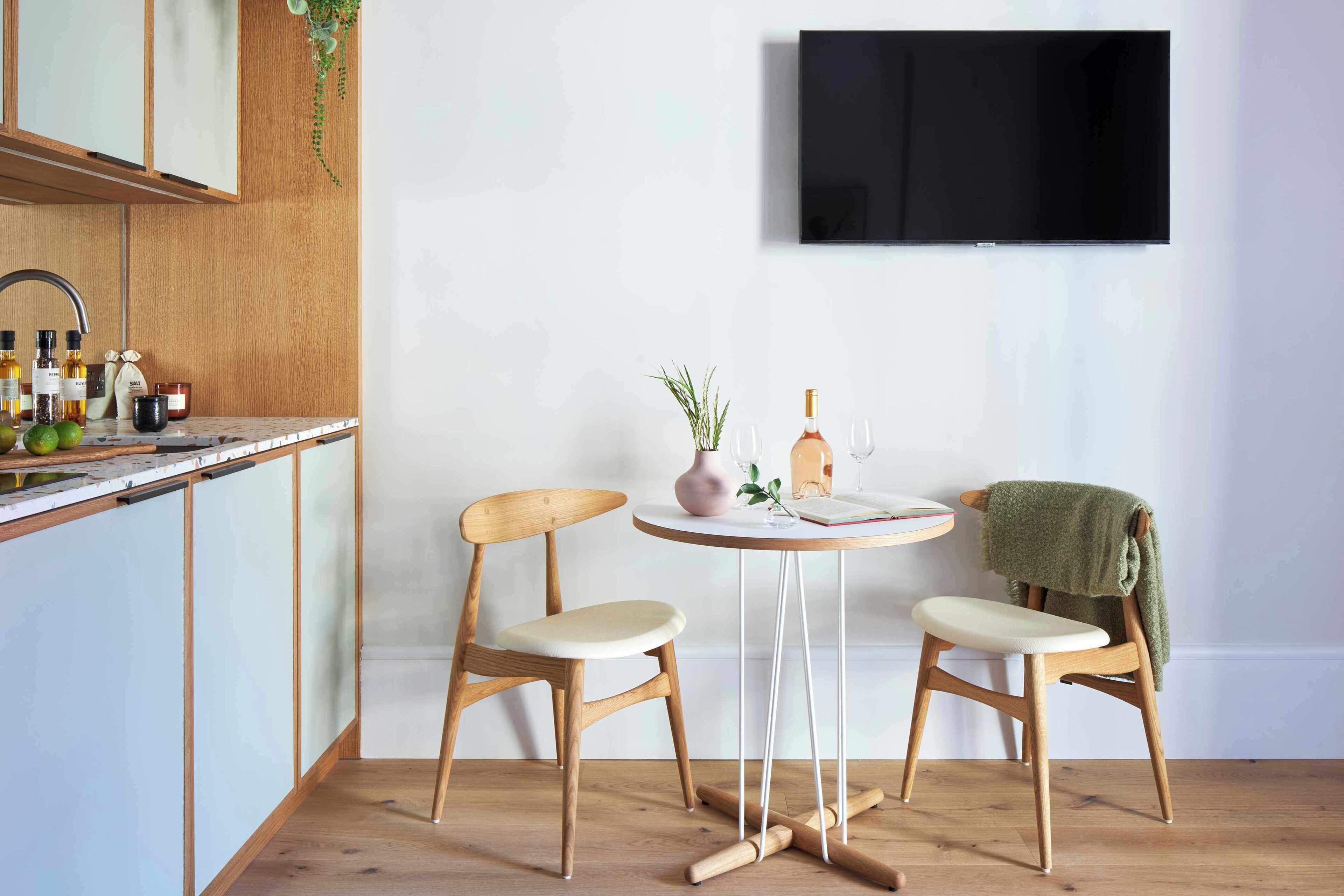 A modern kitchen with wooden cabinets, a built-in sink, and a round table with two chairs.