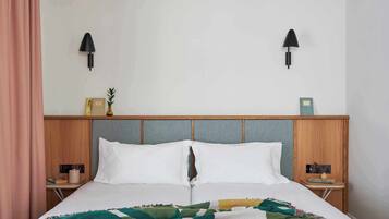 Un lit bien fait, recouvert d’une couverture à motifs, deux tables de chevet avec des lampes et une tête de lit dotée d’une étagère.