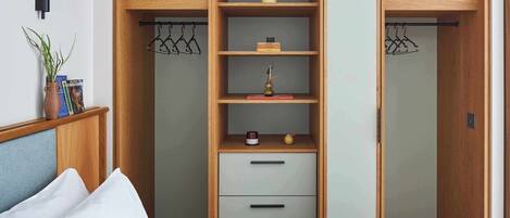 A bedroom with a bed, a nightstand, a wardrobe with multiple compartments, and a wall-mounted lamp.