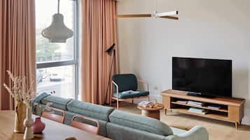 Een moderne woonkamer met een bank, een televisie, een salontafel en een vloerlamp.
