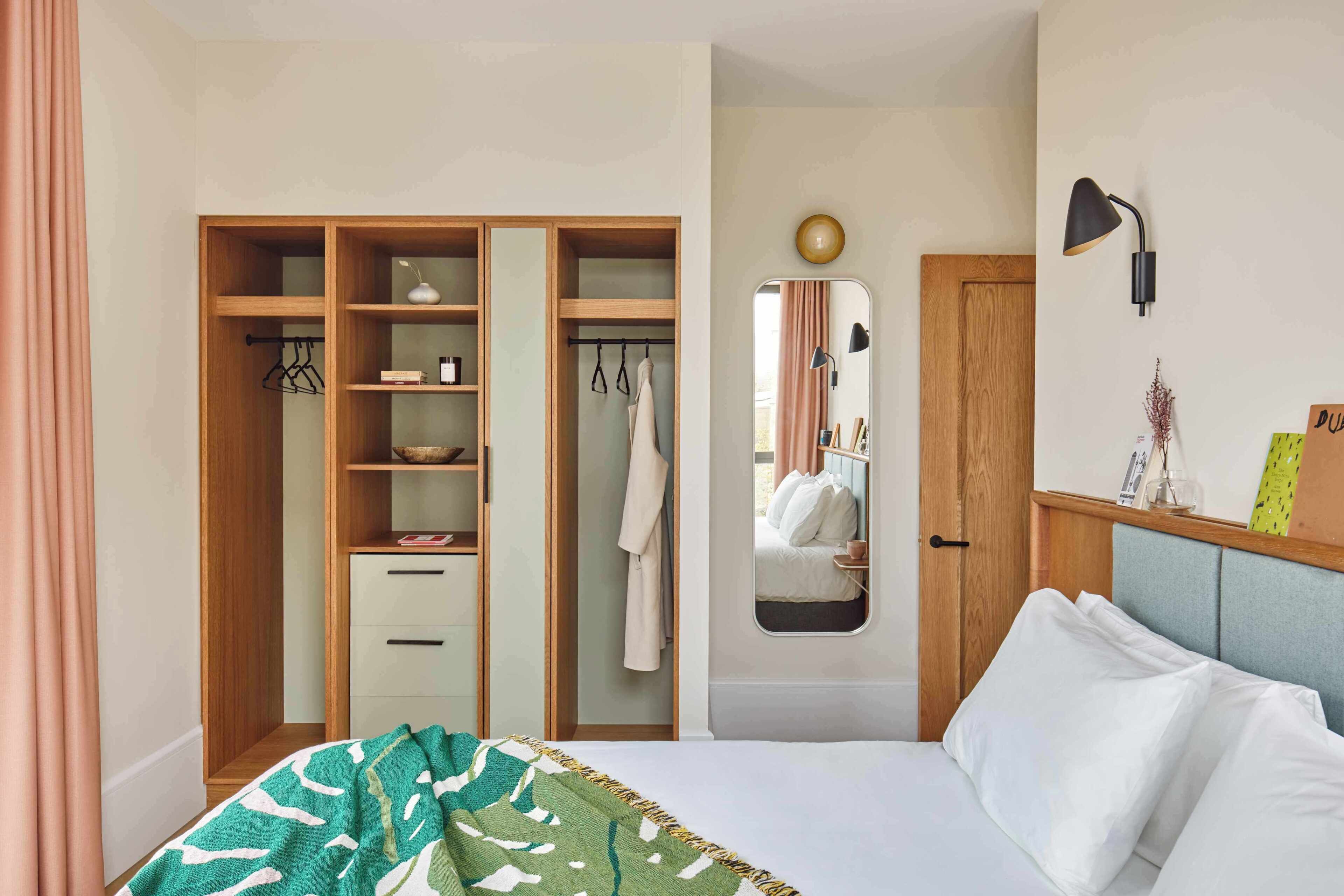 Een slaapkamer met een bed, een kledingkast, een spiegel en een nachtkastje.