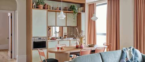 Une cuisine moderne avec un coin repas, des meubles en bois et des luminaires suspendus.