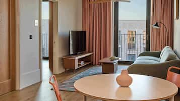 A modern living room with a television, sofa, table, and a view of a building through the window.