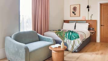 A bedroom with a bed, a sofa, a bedside table, and a window with curtains.