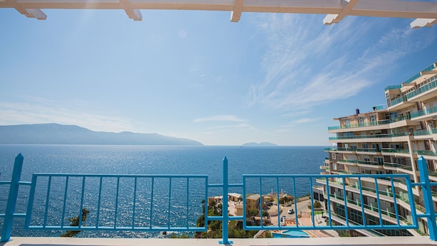 A balcony with a clear view of the sea and distant mountains.