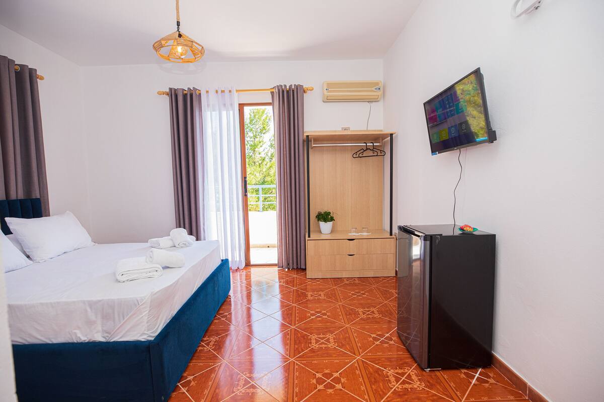 A hotel room with a bed, a desk, a TV, and a wardrobe.