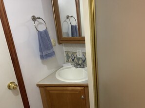 A bathroom with a white sink, a mirror, and a towel hanging on a metal ring. - RV Camper in the heart of Key Largo (Key Largo)