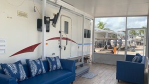 A modern RV interior with a blue sofa, a small couch, and a large window offering a view of the outside. - RV Camper in the heart of Key Largo (Key Largo)