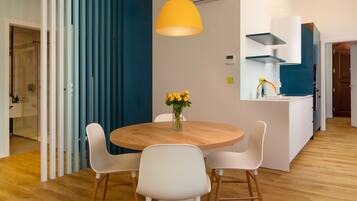 Una cocina moderna con armarios blancos, una mesa de comedor de madera y una lámpara colgante amarilla.
